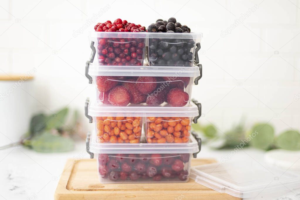 plastic containers with frozen berries on the kitchen table