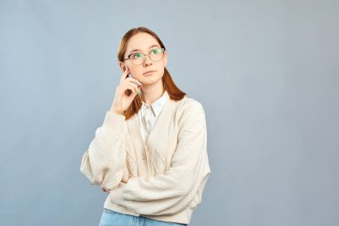 Gri arka planda yalnız poz veren günlük kıyafetli komik bir kadın..