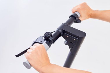 El ele tutuşan e-scooter kulpları. Elektrikli katlama scooter 'ı koyu renkli. Elektrikli scooterın gidonundaki zil..