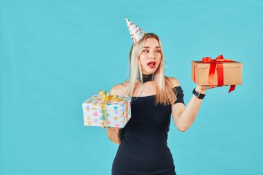 Tatil alışverişi. Kadın doğum günü hediyesi olarak mavi arka planda izole edilmiş iki hediye kutusunu seçiyor. Sevgililer Günü 'nde doğru seçimi düşünen bir kız..