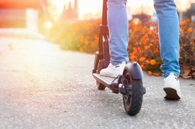 Yenilenebilir enerji ve çevre dostu ulaşım konsepti. Şehirde elektrikli scooter kullanan bir adam. Gelişmiş ulaşım.