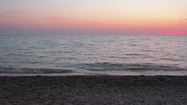 güzel gün batımı manzarası. dalgaların çakıl plajı üzerinde haddeleme