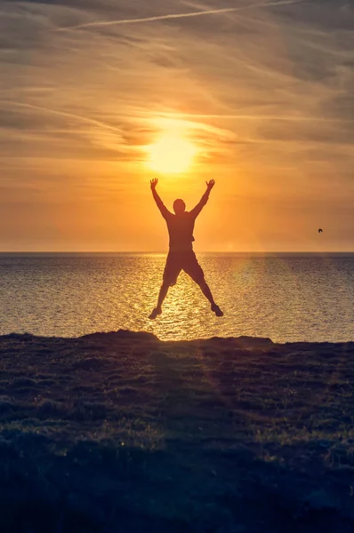 Silhouette eines Mannes, der bei Sonnenaufgang an einen Strand springt — Stockfoto