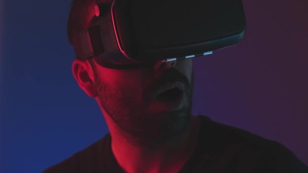 Mladý muž ve VR brýle sluchátka interagovat s virtuální realitou v barvě neonové světlo, budoucí technologie, usmívat vzrušený.Vzdělávání videohry — Stock video