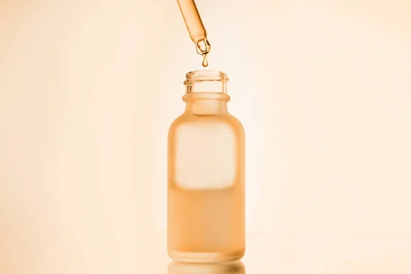 Σταγόνα λάδι ορού προσώπου με σταγονόμετρο γυάλινο μπουκάλι πιπέττα σε κίτρινο φόντο κοντά — Φωτογραφία Αρχείου