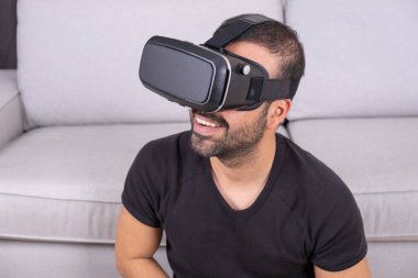 VR gözlüklü genç adam evde sanal gerçeklikle etkileşimde, gülümsüyor. Kapat. gelecek teknolojisi, eğitim video oyunu