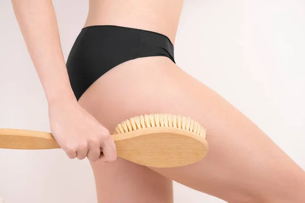 Mulher massageando a pele da perna com uma escova de massagem seca. anti celulite descascamento cuidados com o corpo. Close-up — Fotografia de Stock