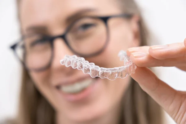 Smiling woman using clear plastic removable braces aligner or whitening tray. dental orthodontic care — Stock Photo, Image