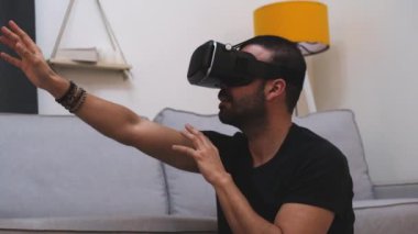 VR gözlüklü genç adam evde sanal gerçeklikle etkileşimde, gülümsüyor. Kapat. gelecek teknolojisi, eğitim video oyunu