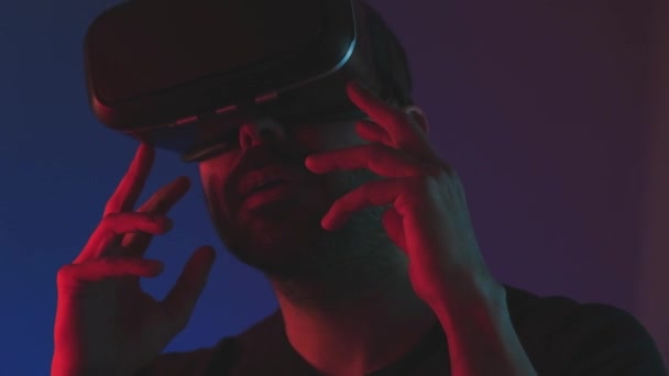 Jongeman in VR bril headset interactie met virtual reality in kleur neon licht, close-up toekomstige technologie, onderwijs video gaming — Stockvideo