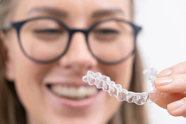 Gülümseyen kadın temiz plastik çıkarılabilir diş teli kullanıyor hizalayıcı ya da beyazlatma tepsisi. Diş ortodonti tedavisi