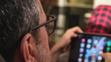 Evdeki dijital tablet monitörüne bakan sakallı bir adamın yakın çekimi. 