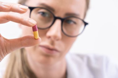 Gözlüklü kadın doktoru kapat. Renkli hap veya kapsül vitamin takviyesi. Yakın çekim.