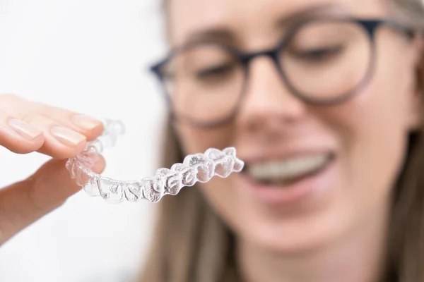 Gülümseyen kadın temiz plastik çıkarılabilir diş teli kullanıyor hizalayıcı ya da beyazlatma tepsisi. Diş ortodonti tedavisi