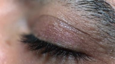 Makro koyu kahverengi göz yavaş çekimde açılıyor ve yanıp sönüyor. Erkekler gözlerini uzun kirpikleriyle açıp kapatıyorlar.