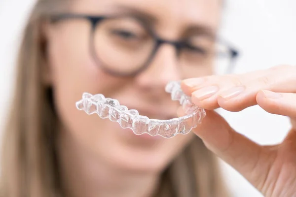 Gülümseyen kadın temiz plastik çıkarılabilir diş teli kullanıyor hizalayıcı ya da beyazlatma tepsisi. Diş ortodonti tedavisi