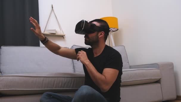 Νεαρός άνδρας με γυαλιά εικονικής πραγματικότητας στο σπίτι που αλληλεπιδρά με την εικονική πραγματικότητα, χαμογελώντας. Κλείσε. μελλοντική τεχνολογία, εκπαιδευτικά βιντεοπαιχνίδια — Αρχείο Βίντεο