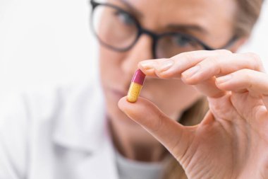 Gözlüklü kadın doktoru kapat. Renkli hap veya kapsül vitamin takviyesi. Yakın çekim.