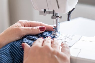 Kadın elleri dikiş makinesinin dikiş malzemelerini kapatır.