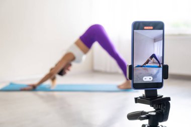woman practicing yoga poses stretching in front of phone camera sport blogger teacher yoga online