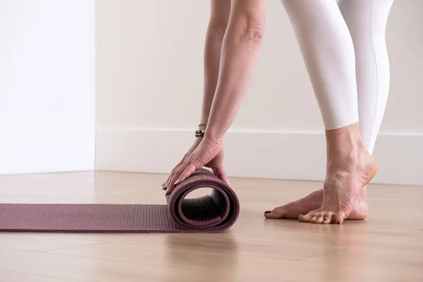 Woman hands rolling yoga mat in studio after practicing yoga workout — Fotografia de Stock