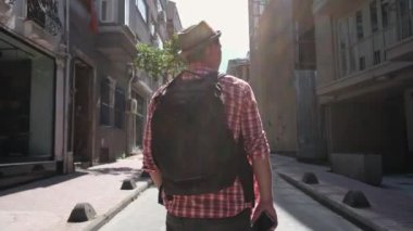 Şapkalı ve sırt çantalı genç bir turist sokaklarda geziyor.