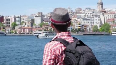 Şapkalı ve sırt çantalı genç bir turist güzel turistik yerlere bakıyor.