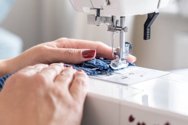 woman hands close up sewing on machine stitching fabric material. 