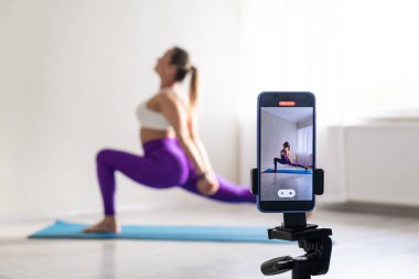 woman practicing yoga poses stretching in front of phone camera sport blogger teacher yoga online class wellness coach