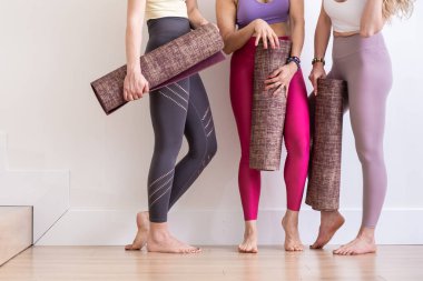 Beyaz stüdyo, yoga hocası, egzersiz ve spor fotokopi alanında yoga minderi tutan üç mutlu genç bayanı kırptım.