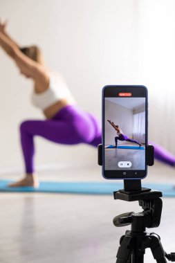 woman practicing yoga poses stretching in front of phone camera sport blogger teacher yoga online class wellness coach