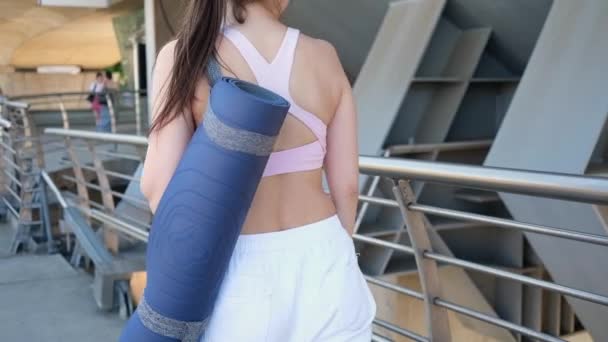Wanita Muda Yang Atletik Dalam Pakaian Olahraga Memegang Tikar Yoga — Stok Video