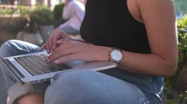 Mutlu genç kadının park yerinde oturup dizlerinin üstünde bilgisayarını yazarken serbest çalışan iş kadını mesajlaşırken.