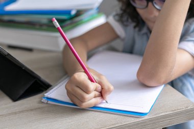 Kıvırcık saçlı, gözlüklü, uzaktan kumandalı, sevimli okul çocuğu. Dijital tablet kullanan konsantre çocuk, video dersinde öğreniyor..