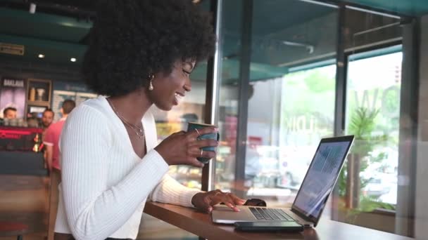 Kafede Oturup Kahve Içen Dizüstü Bilgisayarda Telefonda Çalışan Mutlu Afrikalı — Stok video