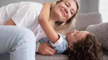 Komik çocuk öpücüğü mutlu anne baba ve anne günü ya da doğum günü gülüşü. Genç bir aile evde birbirine sarılıyor.