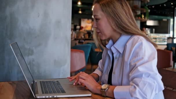 Beyaz Gömlekli Mutlu Genç Bir Kadın Kafeteryada Oturuyor Dizüstü Bilgisayarda — Stok video