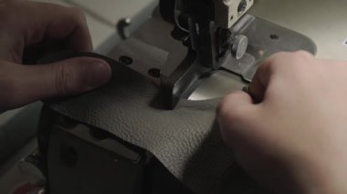 Deri işçiliği. İnsanoğlunun profesyonel endüstriyel dikiş makinesi kullanırken atölyede deri el yapımı ürünler üretmesine yakın çekim.
