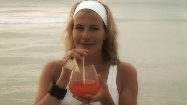 Девушка наслаждается коктейлем на пляже — стоковое видео