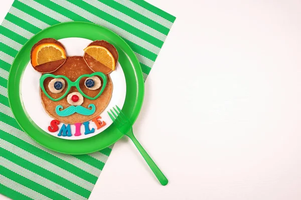 Mâncare amuzantă pentru copii. Clătite în formă de urs sau șoarece, fundal alb, placă verde, șervețel verde. Mâncare sănătoasă pentru copii. Idee creativă pentru micul dejun pentru copii, spațiu de copiere, vedere de sus. — Fotografie, imagine de stoc