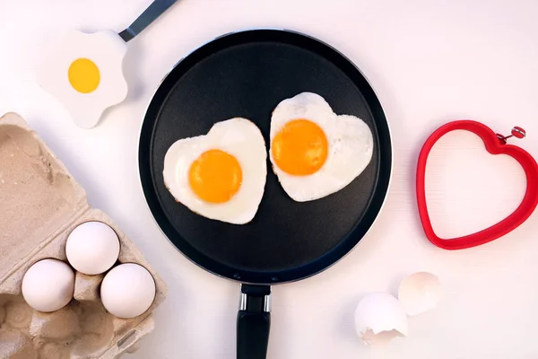 Ouă prăjite în formă de inimă pe o tigaie, fundal alb, vedere de sus. — Fotografie, imagine de stoc