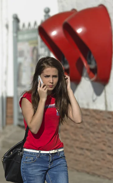 The young beautiful girl goes down the street and speaks by phone — Stock Photo, Image