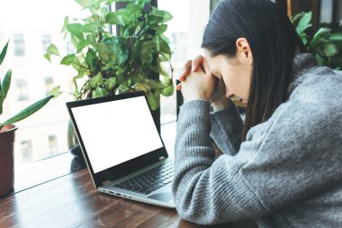 Dizüstü bilgisayarda çalışan yorgun beyaz öğrenci, baş ağrısı ya da migrenden muzdarip..