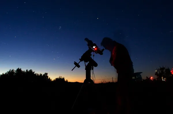 Astronomen tittar genom ett teleskop Royaltyfria Stockfoton