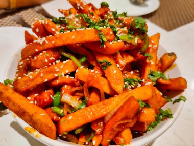 Patatesten yapılmış bir tabağın resmi. Adı bal biberli patates. Gece bir restoranda servis edilen beyaz bir kasede servis ediliyor.