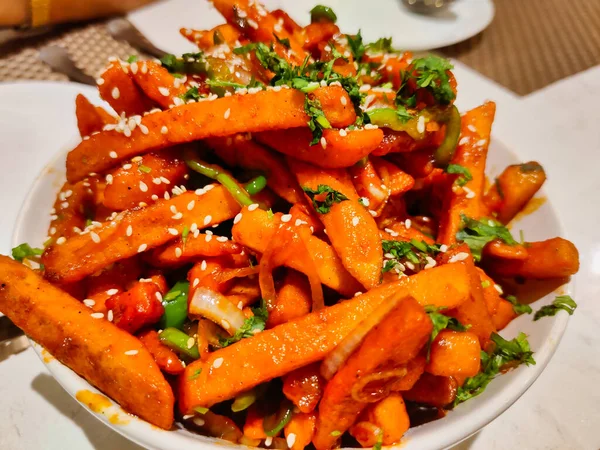 Patatesten yapılmış bir tabağın resmi. Adı bal biberli patates. Gece bir restoranda servis edilen beyaz bir kasede servis ediliyor.