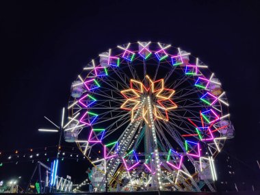 Bir lunaparktaki dev dönme dolabın resmi. Yazları geceleri dönme dolabın etrafında ışıklar yanıyor.