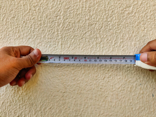 Picture of a measuring tape used by workers for measuring dimensions shot against a light background