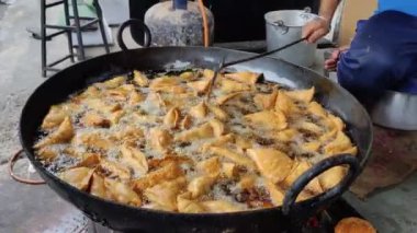 Kızartma kabında sıcak Samosa 'nın görüntüsü. Kızartma tavasında taze Hint usulü leziz köfteler. Hint yemeği (kızarmış hamur işi). Biçimlendirilmiş yemek çekimi