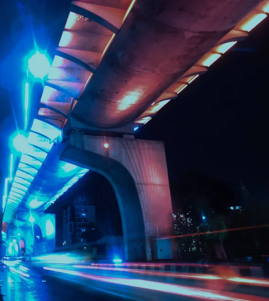 Image of like streaks of vehicles and a flyover illuminated in saffron, white and green